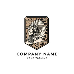 Native American chief in feathered headdress within a shield emblem with tribal patterns, a vintage-style logo design.