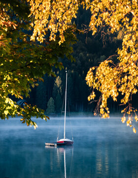 Fototapeta early morning autumn fog and sailboat on the lake