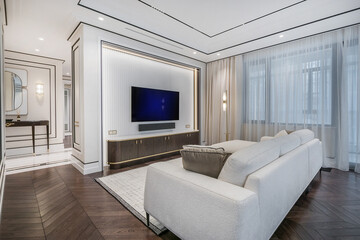 The interior of an elegant neoclassical-style living room with modern furniture and large windows filling the space with soft natural light.