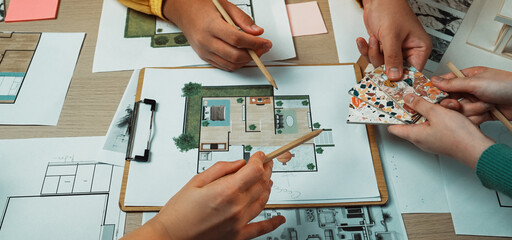 Teams brainstorm and share ideas in a collaborative workspace while reviewing design plans and color swatches for modern interior decoration projects. SACTR