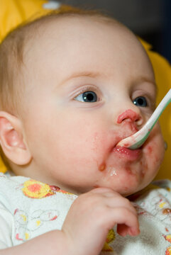 Baby Girl Eating in a High Chair