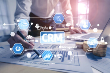 A business professional is analyzing documents with a pen while various customer relationship management icons overlay the workspace, showcasing modern techniques and strategies. Tessel