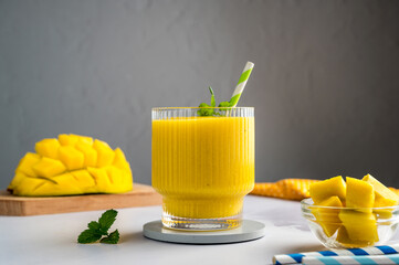Mango banana smoothie in a glass with fresh fruit and mint