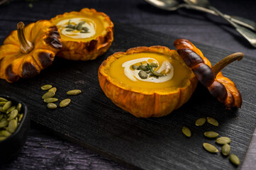 Pumpkin soup in a baked pumpkin bowl, dark background.