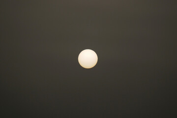 A bright, round sun against a dark, cloudy sky visible during calima on Tenerife.
