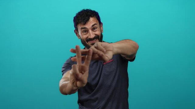 Hispanic man with beard smiling and gesturing hashtag symbol against vibrant blue background.