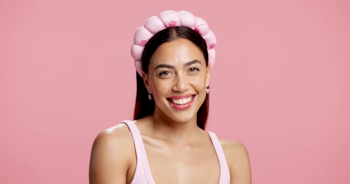 Skincare, happy and woman face with headband in studio, natural glow and beauty routine for facial shine. Dermatology, smile and person with hair band for self care, gen z or space on pink background