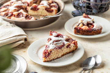 Homemade The New York Times plum cake. Slice of autumn fruit pie in a plate on beige textured background. Home cooking, recipe