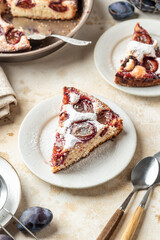 Homemade The New York Times plum cake. Slice of autumn fruit pie in a plate on beige textured background. Home cooking, recipe