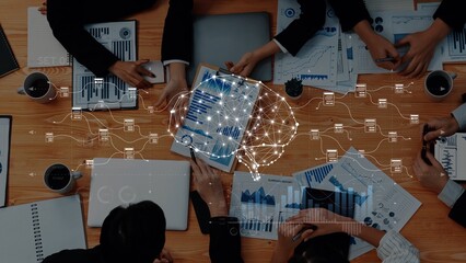 A dynamic business meeting featuring professionals analyzing data through visuals on various devices, with a digital brain overlay symbolizing innovation and insights. Raster