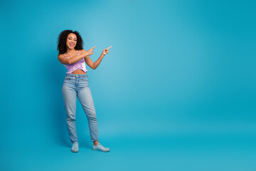 Young glamorous woman in casual fashion points with both hands against a blue background for lifestyle advertising
