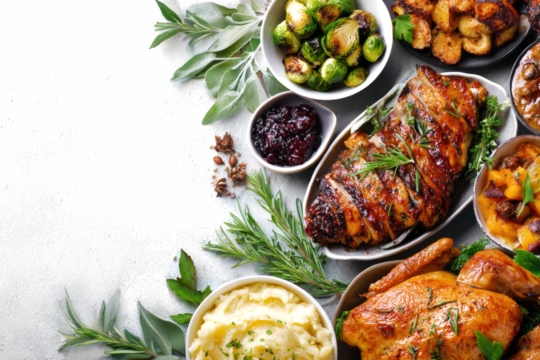 Overhead shot of a Thanksgiving dinner spread featuring turkey brussel sprouts mashed potatoes and cranberry sauce perfect for holiday celebrations