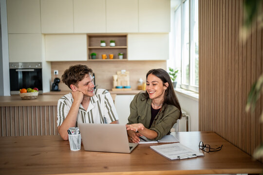 Happy couple planning future together using laptop at home office