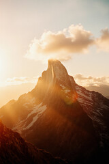 Breathtaking sunset casts warm light on majestic mountain peak with snow-capped ridges in the distance