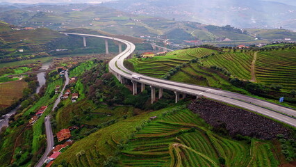 Obraz premium Highway bridge crossing terraced fields in mountain valley. Drone transport line