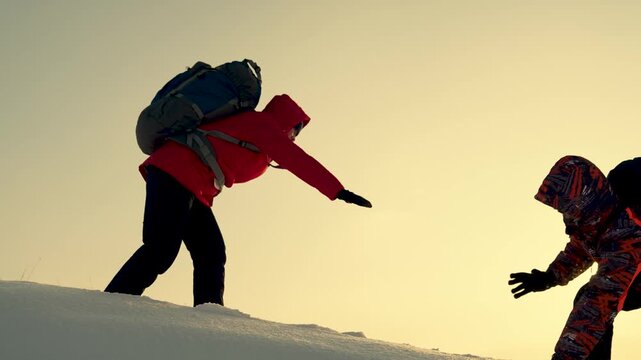 Climbers extend helping hands to each other as they scale snow-capped mountain or hill. Travelers climb snow-capped peak. Working as team of businesspeople. Team of business people strives for victory