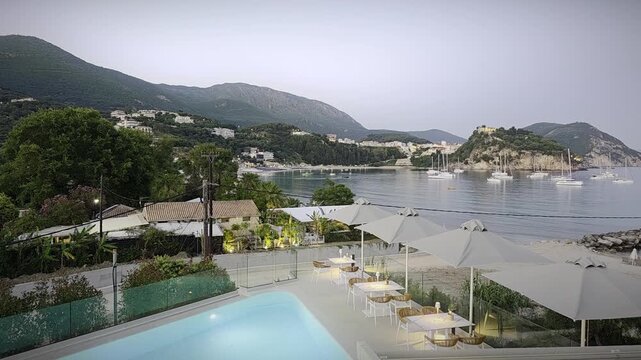 Time-lapse of Parga Greece showing transition from daylight to night. Ionian Sea, Venetian castle, yachts and coastal lights create cinematic sunset view of Mediterranean town.