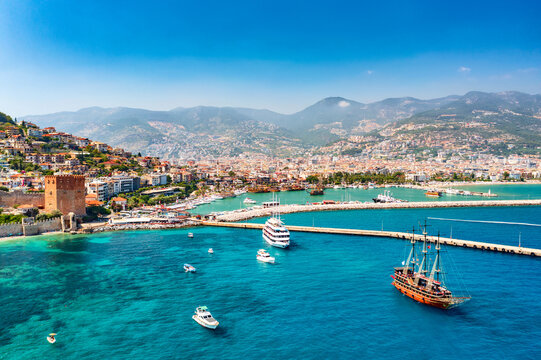Aerial drone view of beautiful harbor with ships and boats and Kizil Kule Red tower in Alanya, Turkey. Summer sunny day