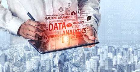 Focused professional writes on a tablet covered with data analytics keywords, symbolizing modern technology integration in business, set against a city backdrop. Tessel