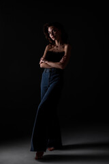 Model poses in stylish outfit with dramatic lighting on dark background