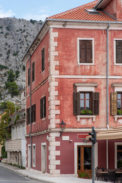 Weathered pink stucco facade with wooden shutters