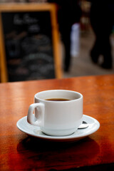 Editable photographic mockup of coffee shop brand logo on cup on sidewalk