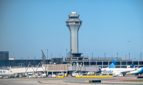 Chicago, Illinois, USA. Oct 4, 2025. O'Hare International Airport control tower oversees bustling tarmac with Alaska Airlines plane under clear skies.