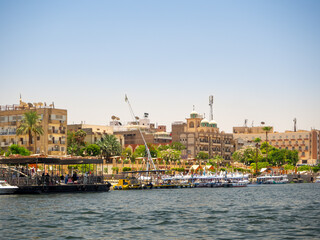 LUXOR, EGYPT : A panoramic view of Luxor’s city skyline along the Nile River, with sunlight reflecting on the water and the city’s historical architecture visible in the background.