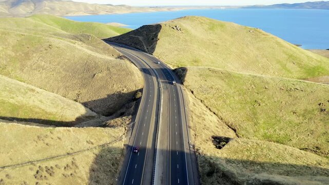Drone shot of Pacheco Pass (CA State Route 152) winding through golden hills near San Luis Reservoir, Central California. Stunning aerial highway view 4k