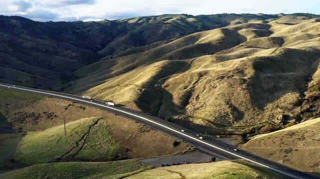 Drone shot of Pacheco Pass (CA State Route 152) winding through golden hills near San Luis Reservoir, Central California. Stunning aerial highway view 4k