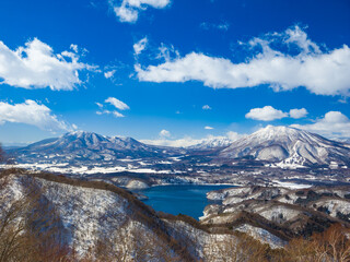 A stunning winter view of the blue Lake Nojiri and the snow-capped mountains of Iizuna and Kurohime (viewed from Madarao, Nagano, Japan)