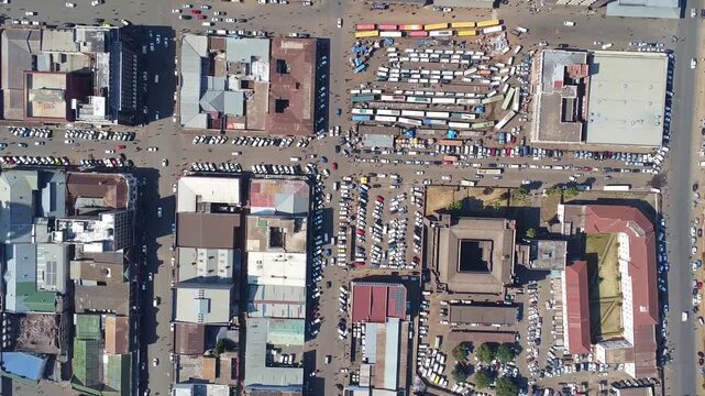 Overhead view of a city intersection with buildings, cars, and people on a bright day