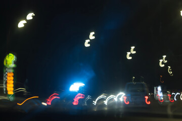 A blurry, atmospheric shot of a city street at night, with dominant blue and yellow lights and a...