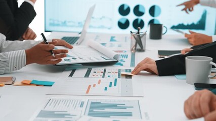 A diverse business team engages in a collaborative session, analyzing data and presenting charts. The environment showcases professionalism and teamwork in an office setting. SACTR - Powered by Adobe