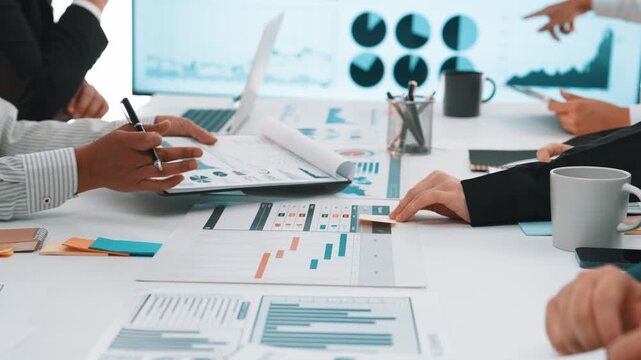 A diverse business team engages in a collaborative session, analyzing data and presenting charts. The environment showcases professionalism and teamwork in an office setting. SACTR