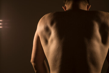 Back view of muscular strong man posing. Sensual. Strong body man. Diet. Photo. Model. Background. Shadow. Sports. 