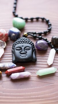 A Black Buddha Necklace and Assorted Healing Stones on a Wooden Surface	