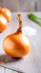 Single yellow onion on a light-colored wooden surface