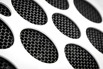 Abstract background of a white circle pattern over black metal mesh