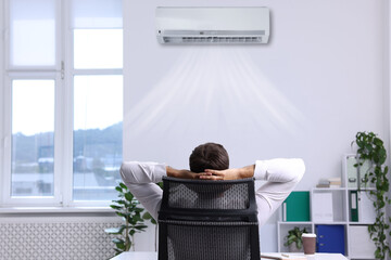 Worker under air conditioner in office. Keeping comfortable temperature