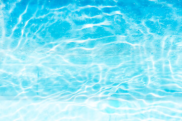 Blue water with ripples on the surface. Defocus blurred transparent blue colored clear calm water surface texture with splashes and bubbles. Water waves with shining pattern texture background.
