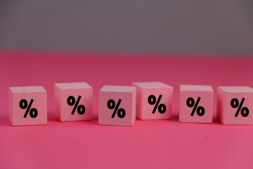 pink wooden cube with Percentage Symbol on Dice Representing Budget Cut Interest Rate Reduction Financial Decision and Economic Adjustment Concept. 
