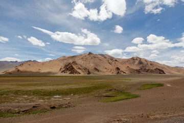 Vast arid mountain landscape under a blue sky with clouds