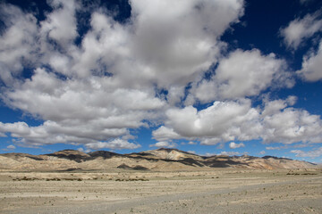 Vast desert landscape under a blue sky with scattered clouds