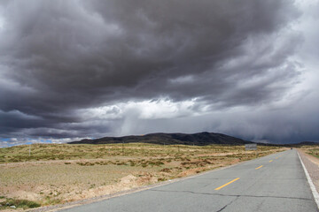 Stormy clouds looming over an empty road in a vast plain