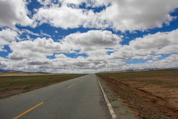 A Long Road Under a Vast Sky with Fluffy Clouds