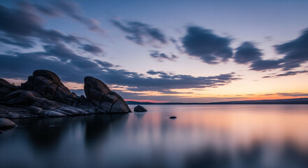 Serene Sunset over Rocky Shoreline, Blurry Water Reflections