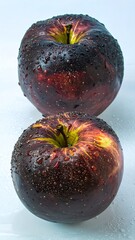 Two dark purple and green apples