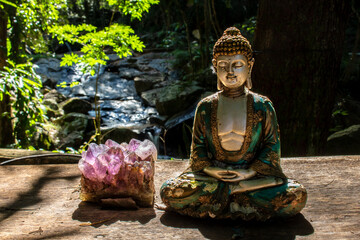 Meditating Buddha statue and amethyst in a serene natural setting in Brazil, symbolizing peace and spirituality.