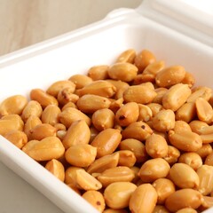 Roasted peanuts in a white container